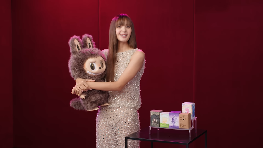 A curiosidade e vontade de participar das tendências explica a explosão das Labubus, inicialmente adotadas pela cantora Lisa, do grupo de K-pop Blackpink (Imagem: Vanity Fair/Youtube/Divulgação)