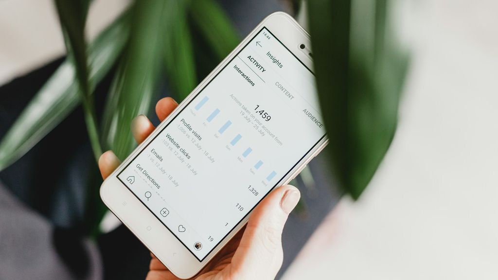 Mão segurando um celular com os insights do Instagram aberto
