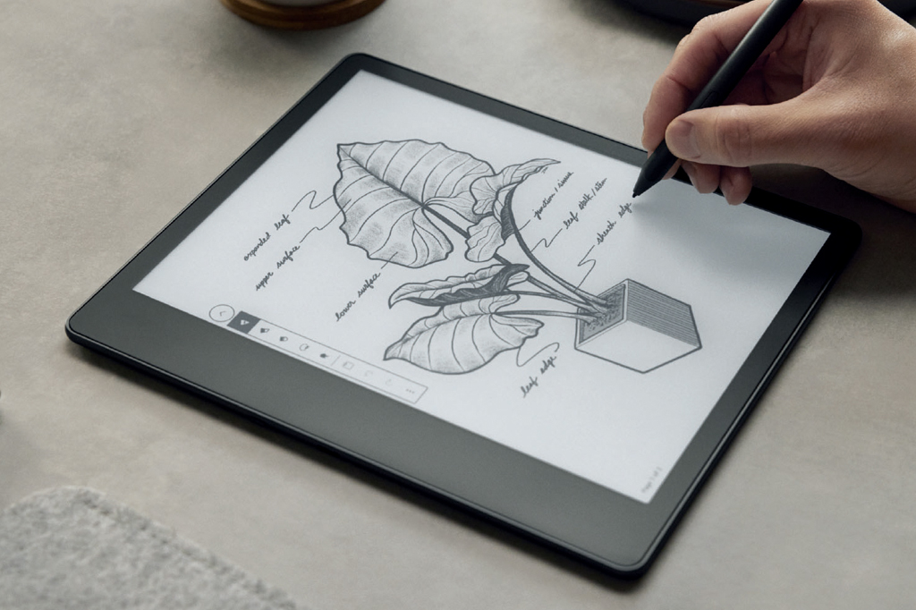 Imagem de uma mão masculina segurando uma caneta ótica para Kindle. Na tela vê-se um desenho de um vaso com uma planta de grande folhagem.