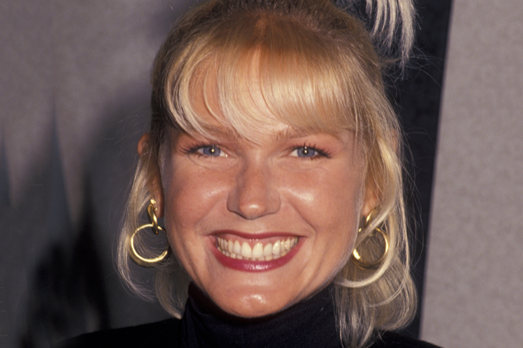 Imagem de uma mulher sorrindo, usando brincos e cabelos loiros.