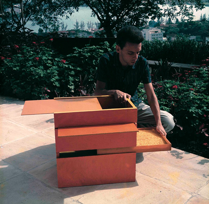 Fotografia do Hélio Oiticica manipulando o trabalho B 11 Bólide caixa 9 (1964).
