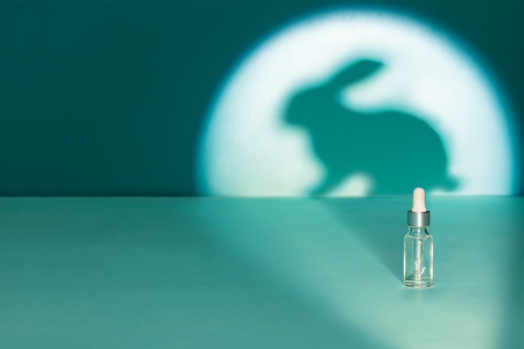 Imagem, de tom esverdeado, projetando a sombra de um coelho na parede. Em primeiro plano, vê-se, um frasco conta gotas de vidro.