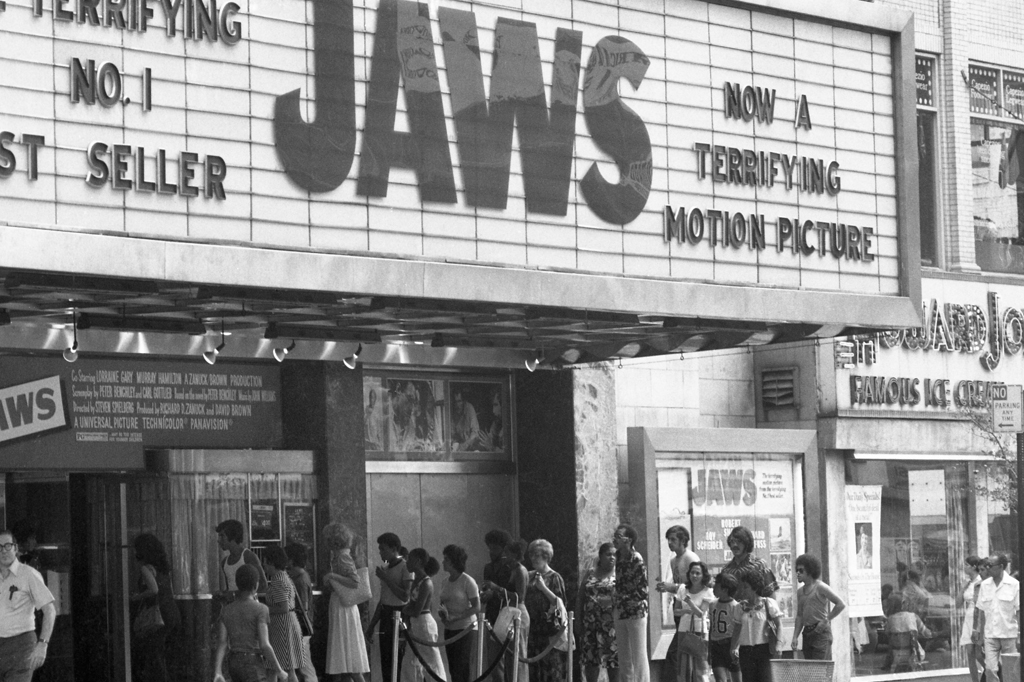 Imagem de um grupo de pessoas formando fila na porta de um cinema.