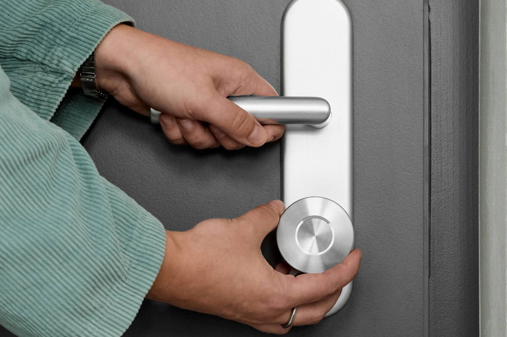 Imagem, focada nas mãos, de uma pessoa abrindo uma porta.