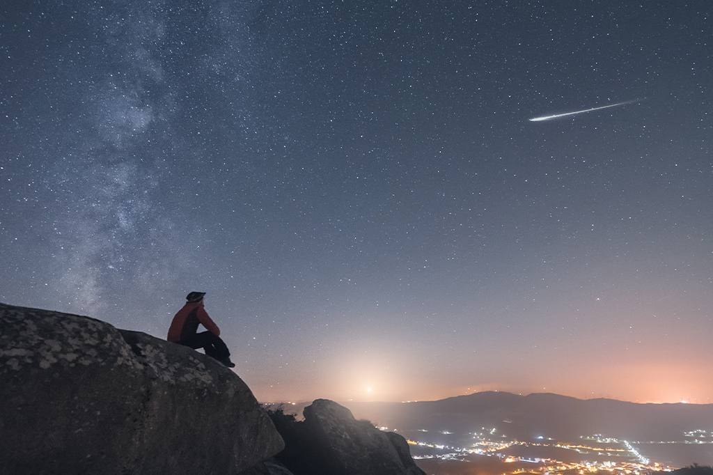 Um homem observando uma estrela cadente.