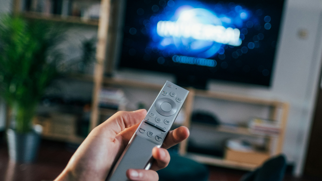 Pessoa muda canal da TV no controle remoto