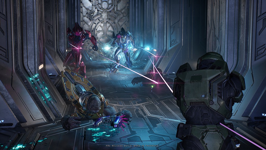 Cena de jogo com três personagens futuristas em combate. Um soldado verde está de costas, atirando raios roxos em dois inimigos: um vermelho e outro azul, ambos com armaduras brilhantes. Um terceiro inimigo, de armadura dourada, está caído no chão, com uma arma roxa ao lado. O cenário é uma estrutura metálica escura com detalhes luminosos azuis