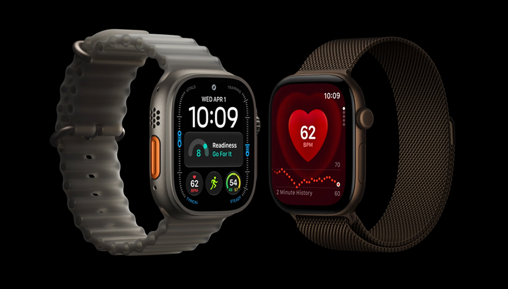 Dois smartwatches em fundo preto. À esquerda, um relógio cinza com pulseira branca exibe hora, data e dados de atividade física. À direita, um relógio marrom com pulseira de malha mostra a frequência cardíaca de 62 BPM em um gráfico vermelho